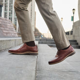 Model walking on stairs wearing The Original Chestnut paired with light brown dress pants
