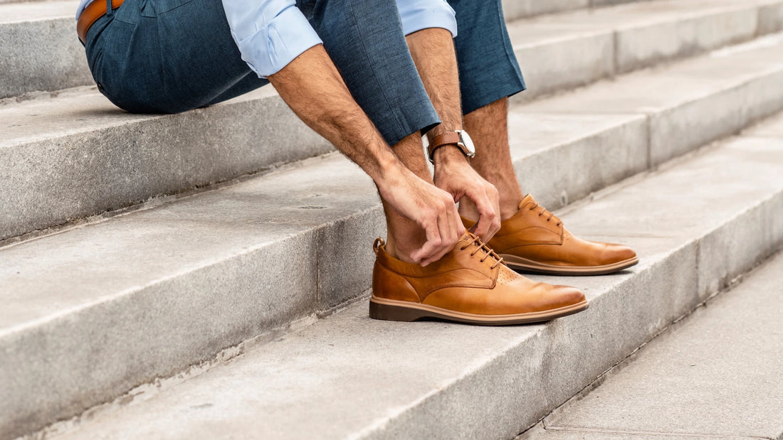 A man in blue jeans wearing a pair of tan dress shoes for men 