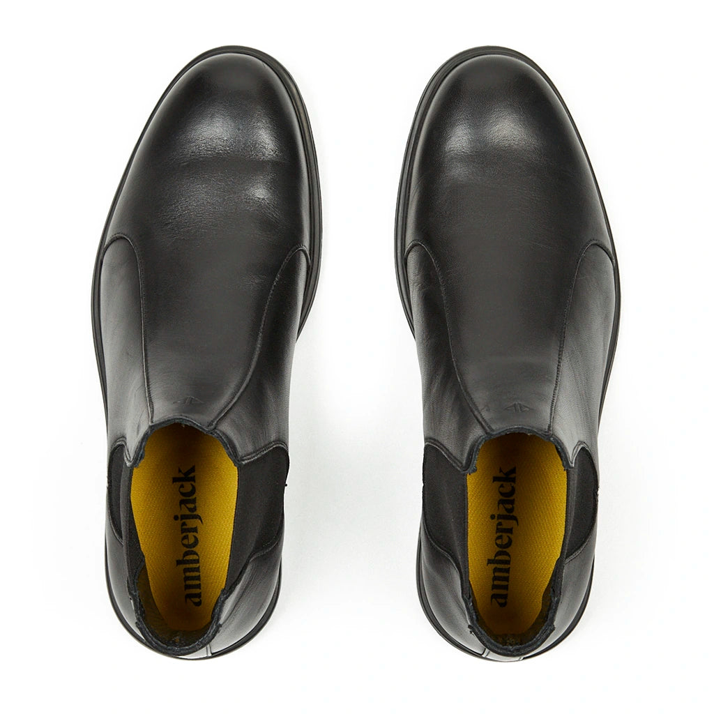 Top view of black leather slip-on shoes with yellow insoles marked 'amberjack'.